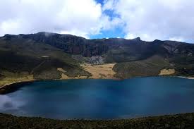 A calm view of Lake Alice on Mount Kenya, surrounded by open alpine meadows and gentle high-altitude slopes near Mugi Hill on the Chogoria Route.